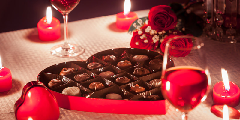 awesome gifts   table set with wine glasses, candles and box of chocolates